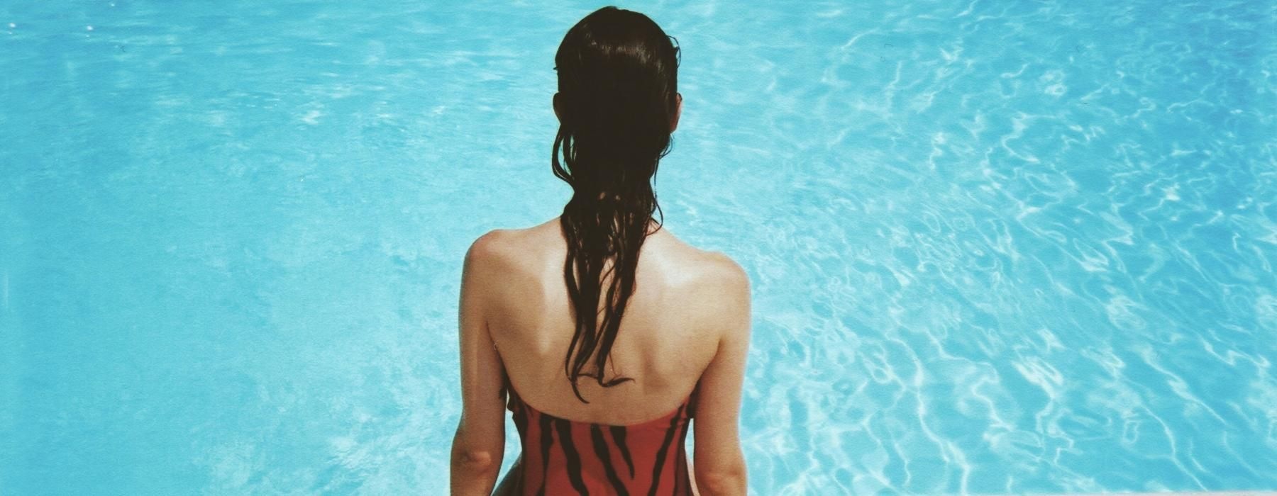 a person sitting on a ledge looking at the water