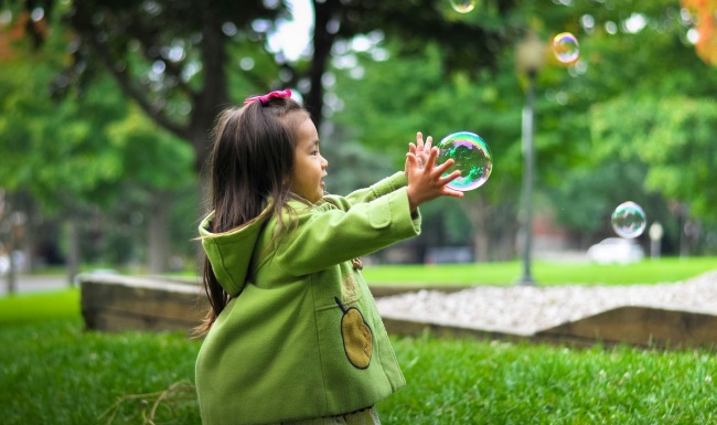 A perfect fit for the whole family A girl playing in the park with bubbles
